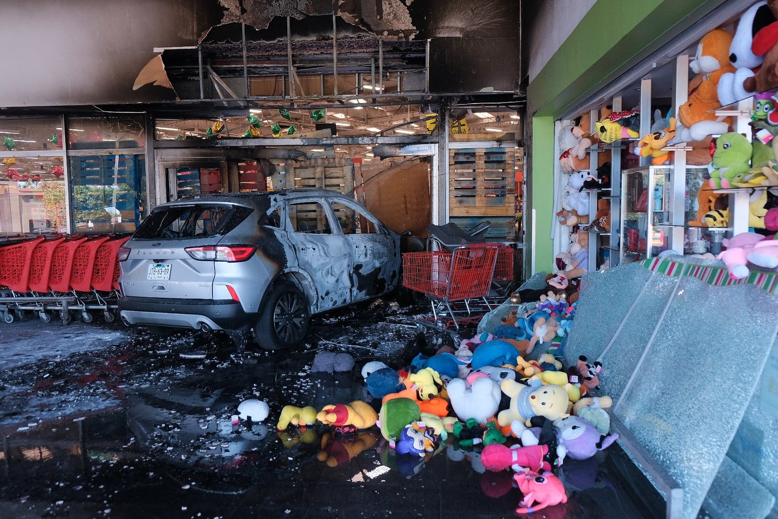 A charred vehicle sits at a damaged supermarket in Guadalajara, Jalisco state, Mexico, Sunday, Feb. 22, 2026, after the death of the leader of the Jalisco New Generation Cartel, Nemesio Rubén Oseguera Cervantes, known as 