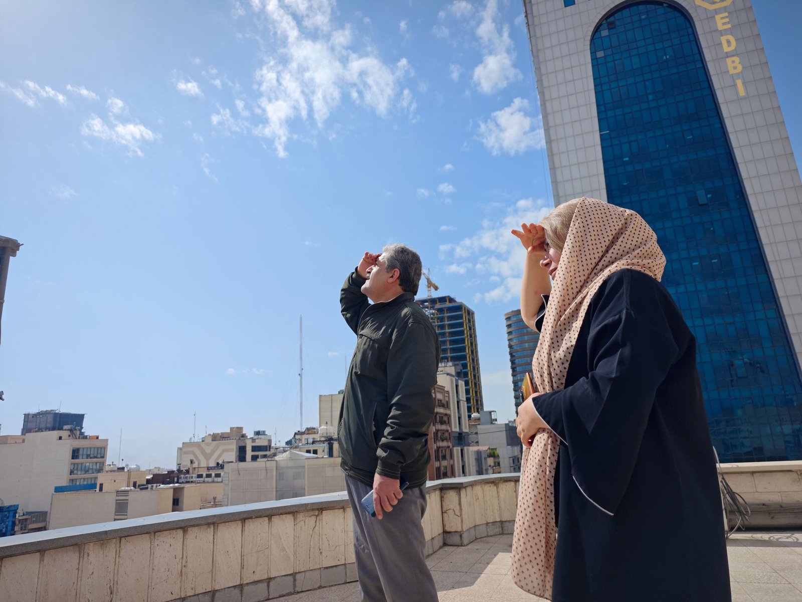 People look the skies from a rooftop amid reports of widespread attacks in the country by the United States and Israel on February 28, 2026 in Tehran, Iran.