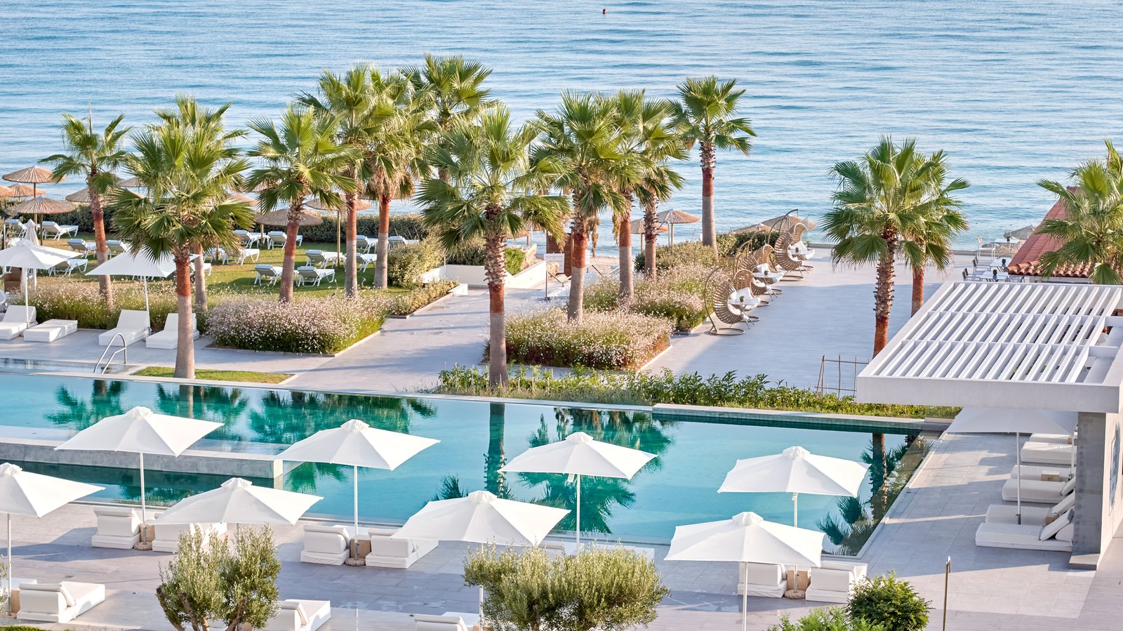 The pool area at Domes Noruz Kassandra overlooks a calm stretch of beach