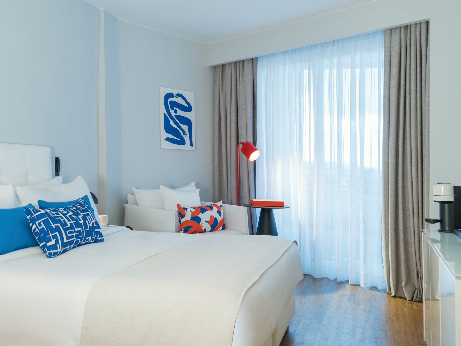 An Ivory Retreat room at Domes Noruz Kassandra, featuring minimal interiors with pops of colour from local artwork