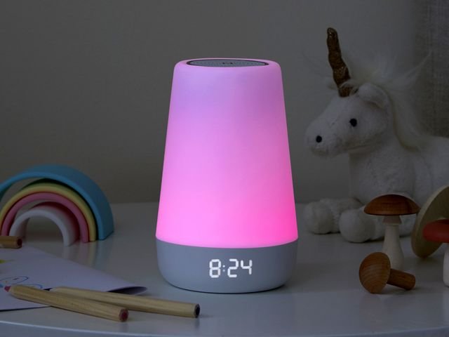 Hatch Rest 2nd Gen sitting on kid's bedside table, glowing pink