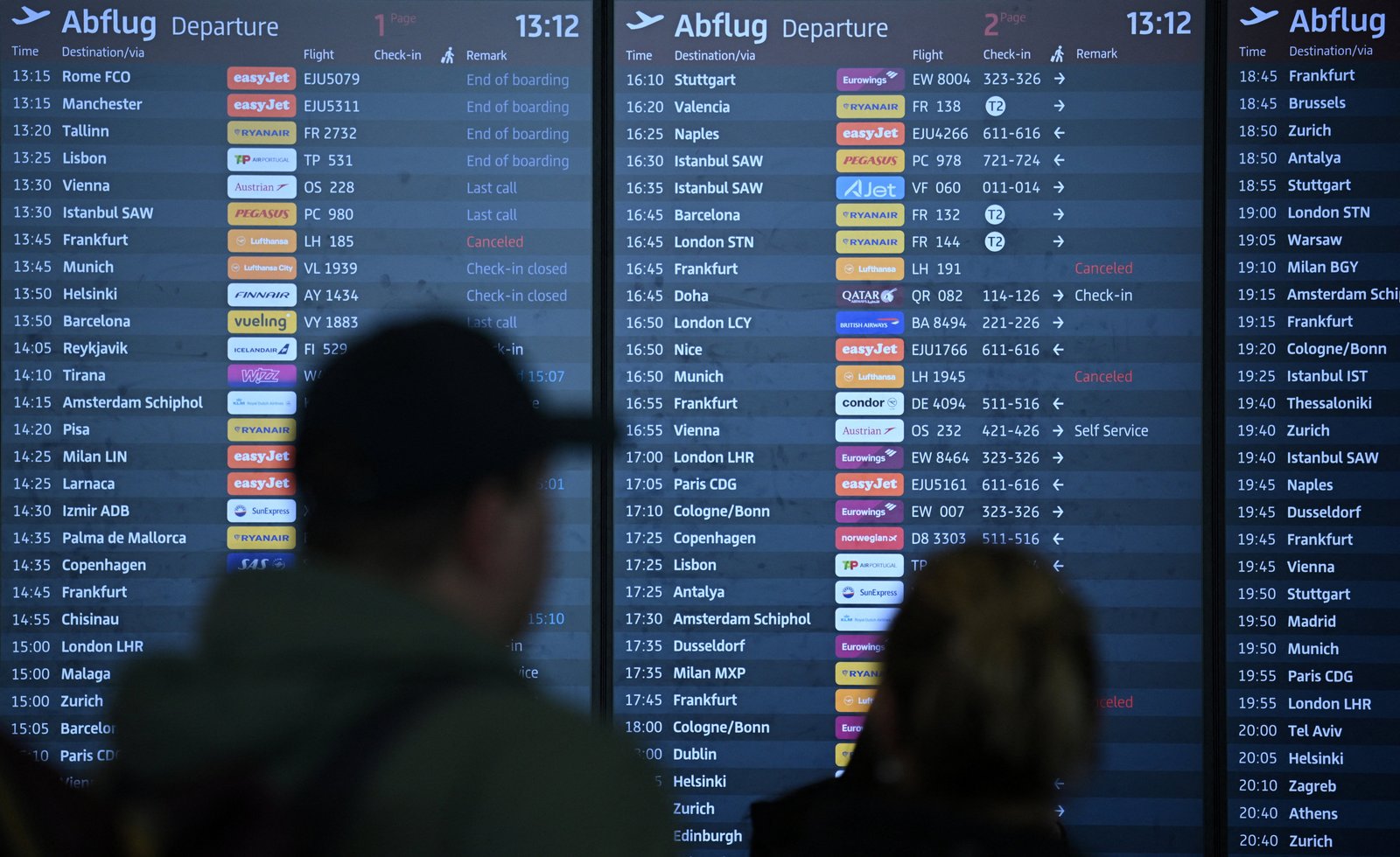 People walk past an information panel, showing cancelled Lufthansa flights during a strike of Cockpit, the union representing Lufthansa pilots.