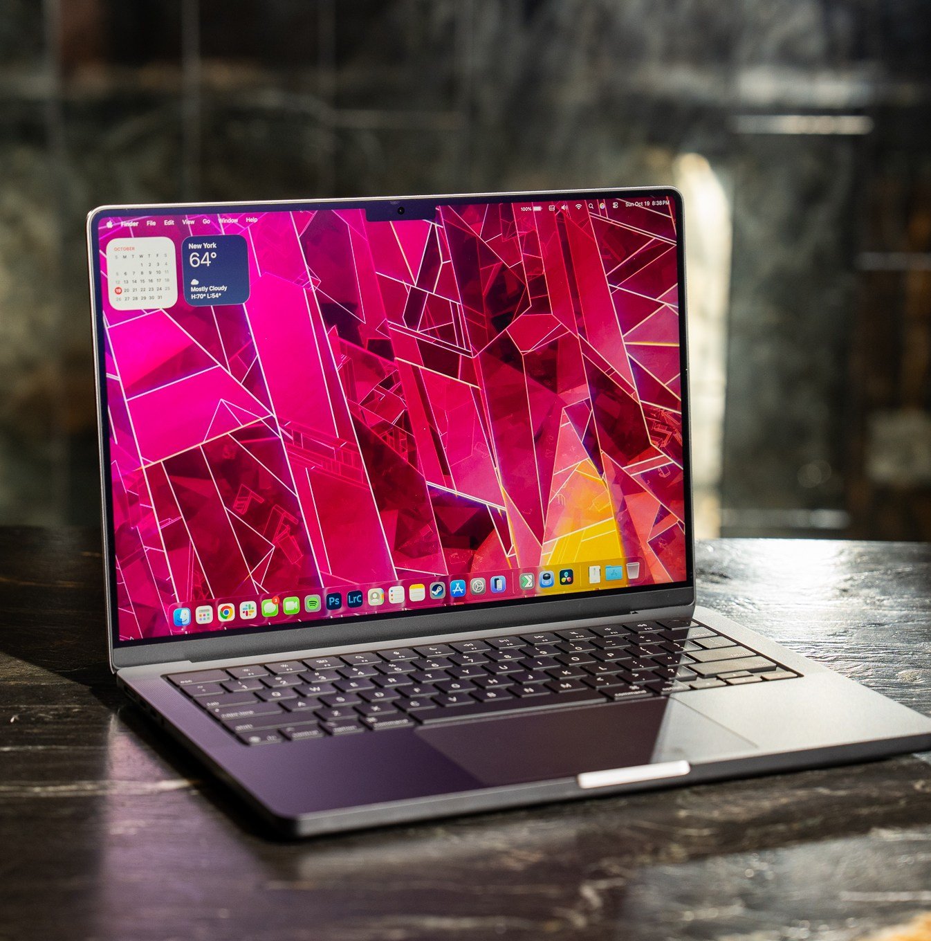 A 2025 14-inch MacBook Pro M5 on a marble bar top with a dark mirrored reflection behind it.