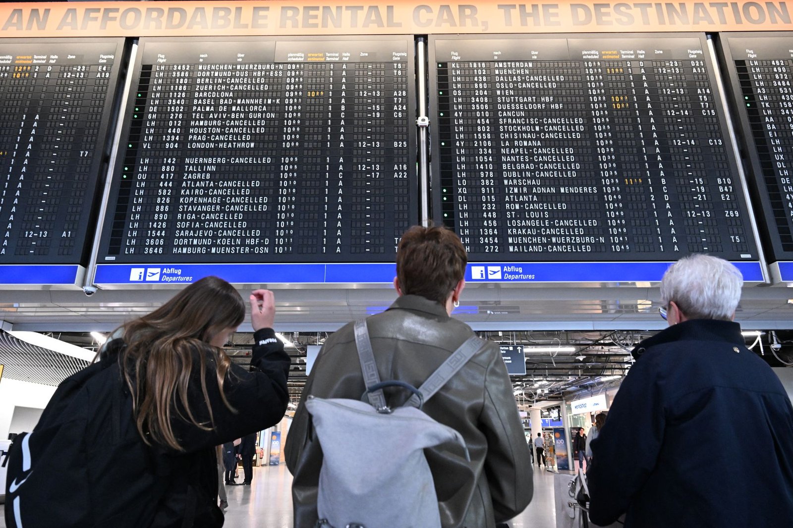 Passengers look at the announcement board showing cancelled flights at Frankfurt Airport in Frankfurt am Main
