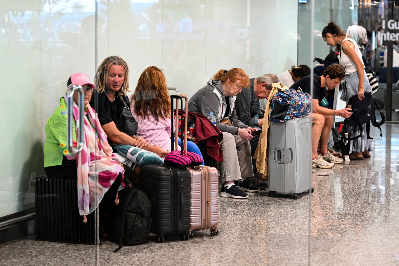 Passengers wait amid flight disruptions as a result of the Israeli-US strikes on Iran, at Ngurah Rai International Airport on Indonesia's resort island of Bali.