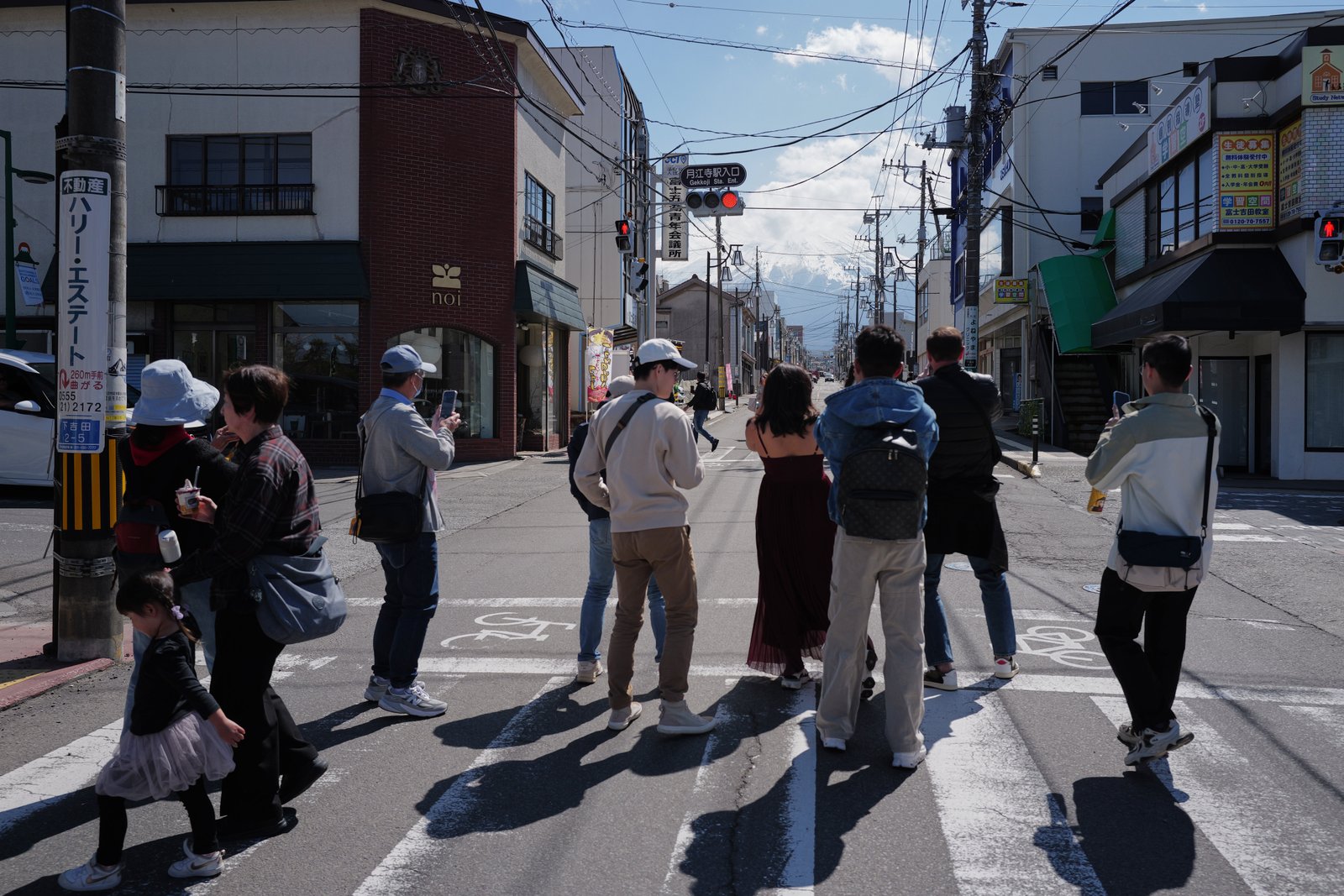 Tourists stand in the street to take photos of Mount Fuji