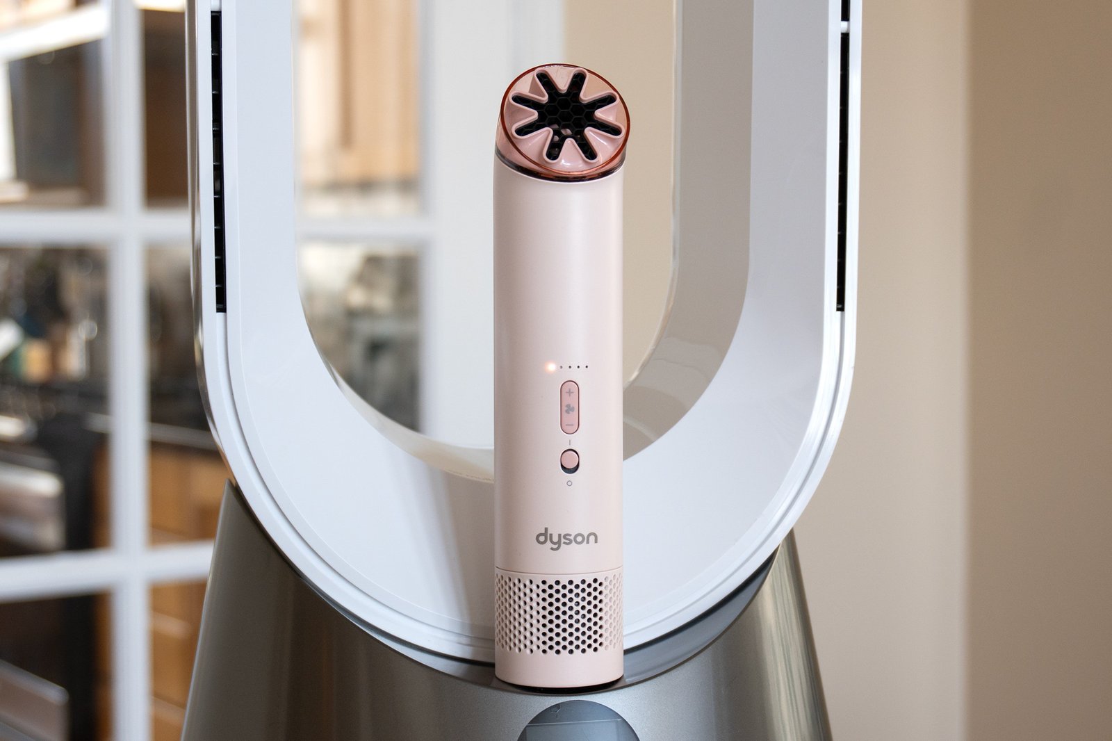 The Dyson HushJet Mini Cool fan sitting on the front of a larger Dyson house fan.